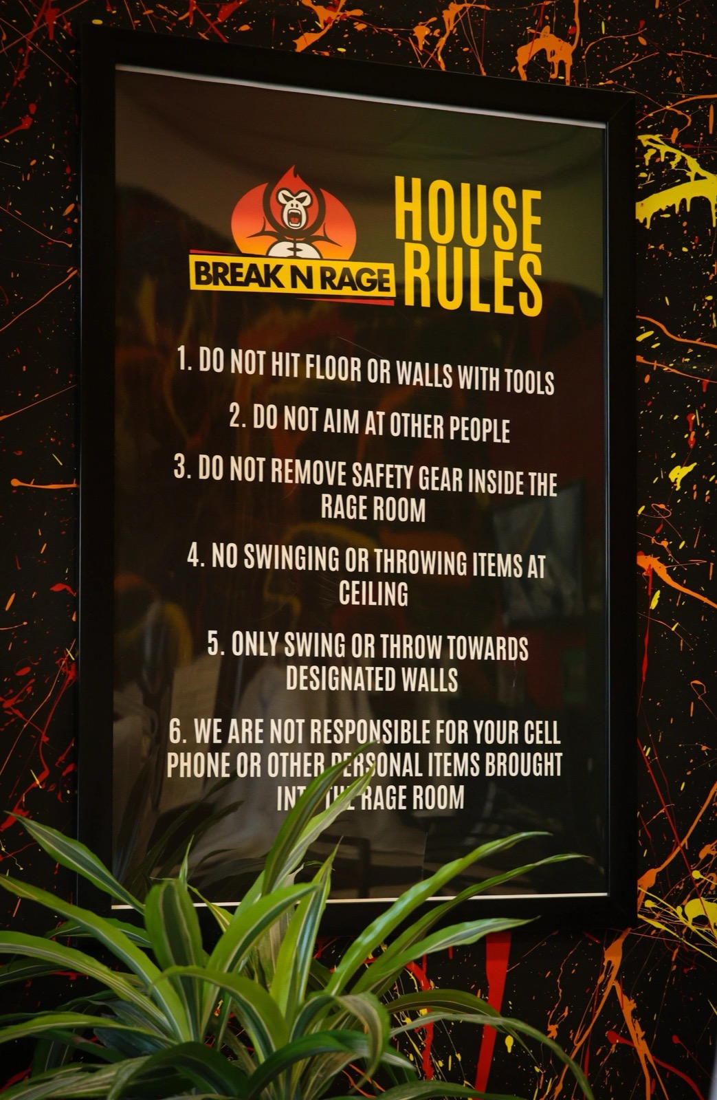Break N Rage's framed house rules board on a paint-splattered black wall