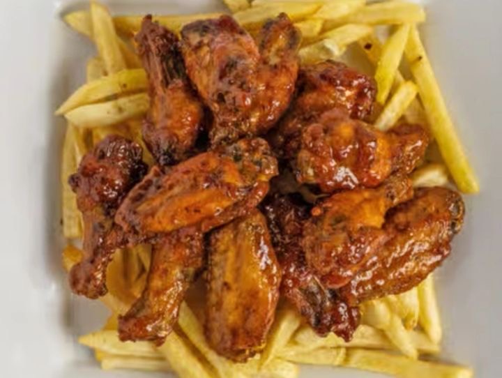 Sticky honey garlic wings with a glazed amber coating, served over fries
