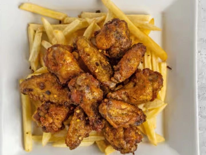 Dry-rubbed lemon pepper wings served on a bed of fries