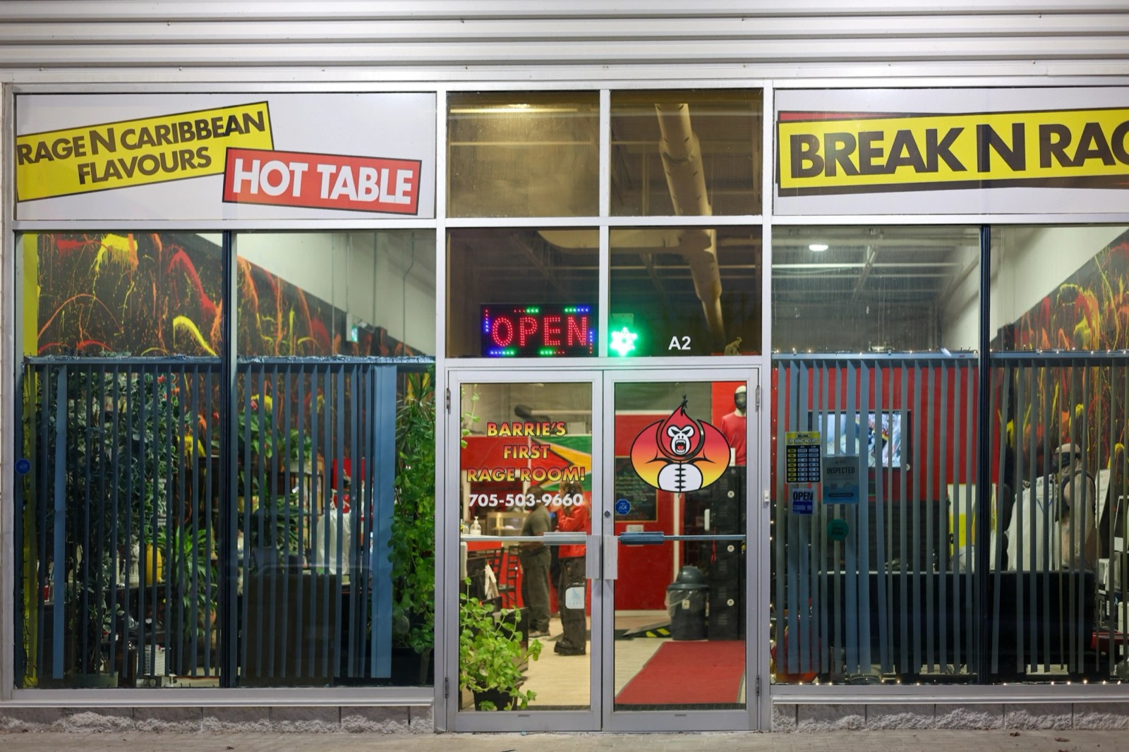 The Break N Rage storefront at unit A2 in Commerce Park, lit up at night with an OPEN sign